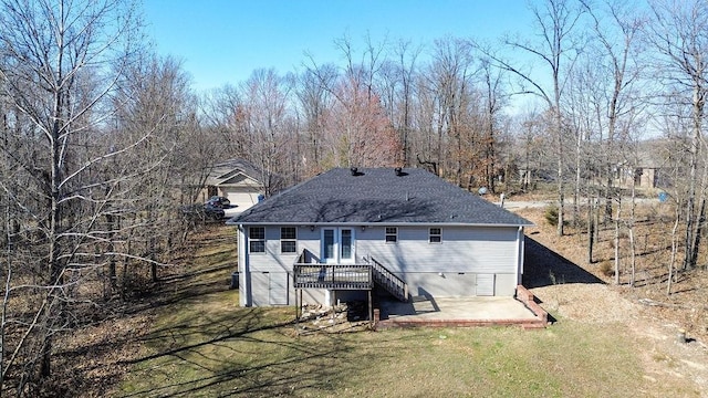 rear view of house with a shingled roof, stairway, a wooden deck, a lawn, and a patio