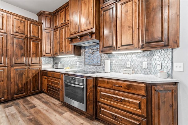 kitchen with decorative backsplash, light countertops, oven, and black electric stovetop