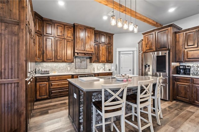 kitchen featuring decorative backsplash, light countertops, dark wood-style floors, and stainless steel refrigerator with ice dispenser