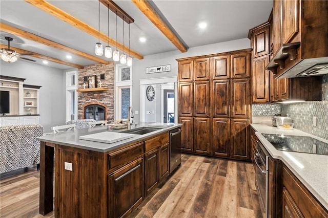 kitchen with premium range hood, a sink, open floor plan, a stone fireplace, and dishwasher