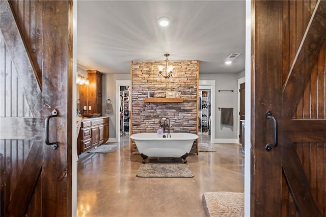 full bath featuring visible vents, concrete floors, baseboards, an inviting chandelier, and a soaking tub