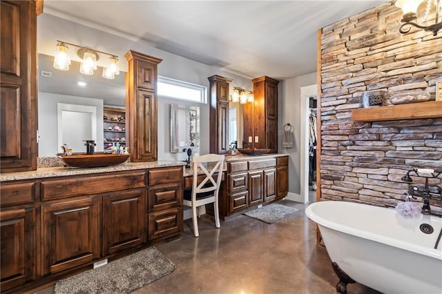 full bath featuring vanity, a freestanding bath, and concrete floors