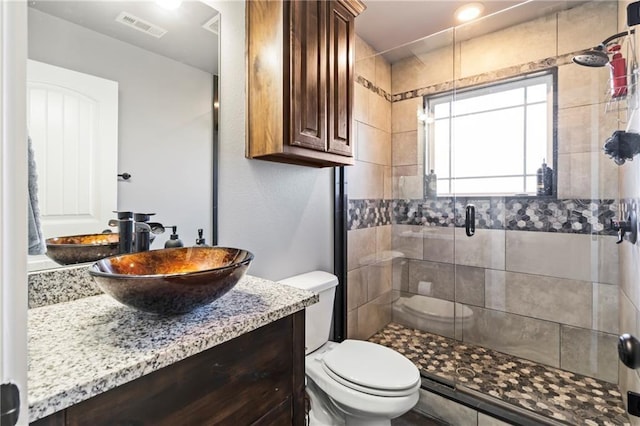 full bathroom featuring visible vents, a stall shower, toilet, and vanity