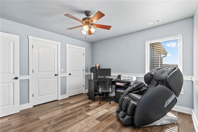 office area with baseboards, wood finished floors, visible vents, and ceiling fan