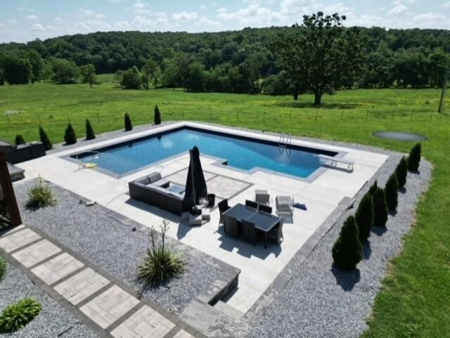 outdoor pool with a lawn, a patio, and fence