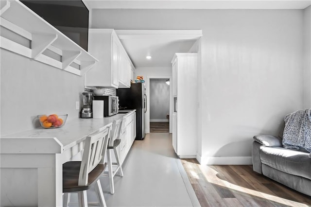 kitchen featuring open shelves, stainless steel appliances, light wood-style floors, white cabinets, and baseboards