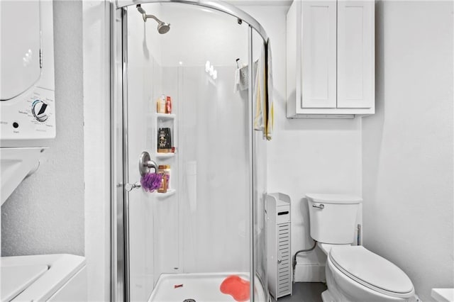 full bath featuring toilet, a stall shower, and stacked washing maching and dryer