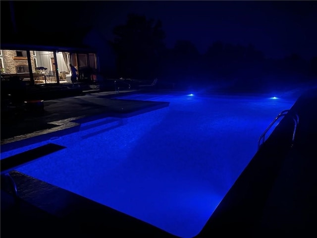 pool at night featuring a patio