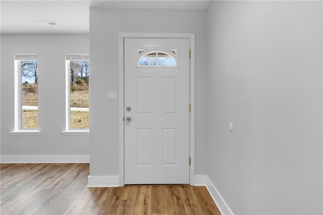 foyer entrance with visible vents, baseboards, and light wood-type flooring