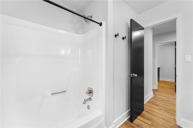 bathroom featuring shower / tub combination, wood finished floors, and baseboards