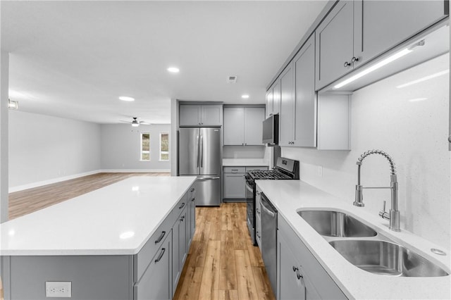 kitchen with a sink, gray cabinetry, a ceiling fan, and stainless steel appliances