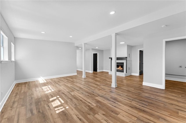 basement featuring recessed lighting, a fireplace, baseboards, and wood finished floors