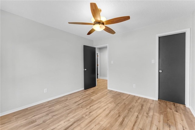 spare room with a textured ceiling, baseboards, light wood-style floors, and ceiling fan