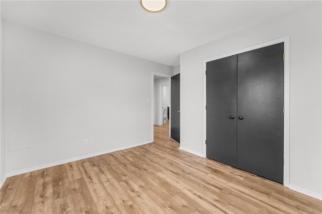 unfurnished bedroom featuring a closet, baseboards, and light wood finished floors