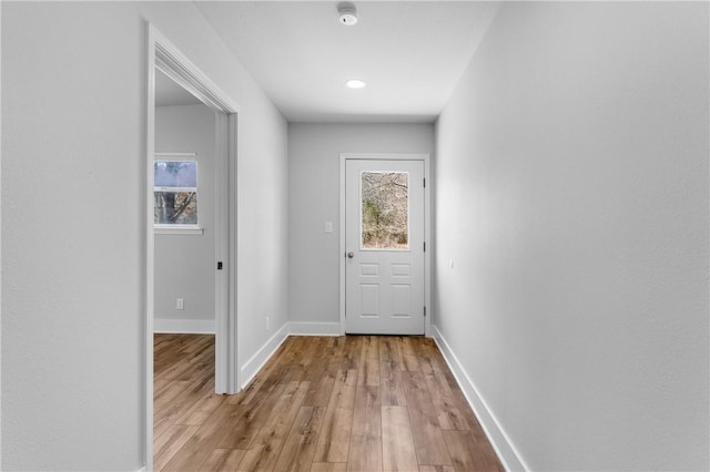 doorway to outside with a healthy amount of sunlight, light wood-style floors, and baseboards