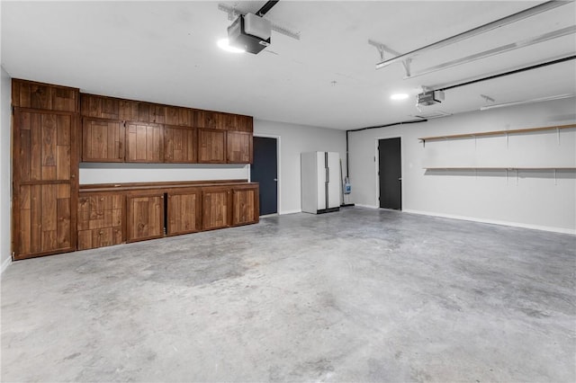 garage featuring a garage door opener, baseboards, and freestanding refrigerator