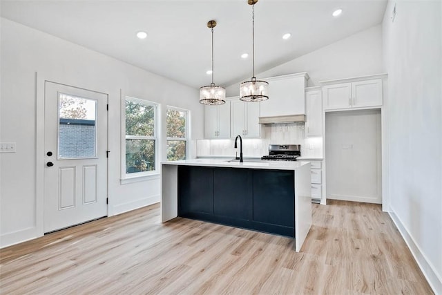 kitchen with a sink, stainless steel range oven, tasteful backsplash, white cabinetry, and light countertops