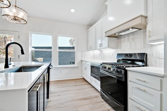 kitchen with light countertops, custom range hood, decorative backsplash, black appliances, and a sink