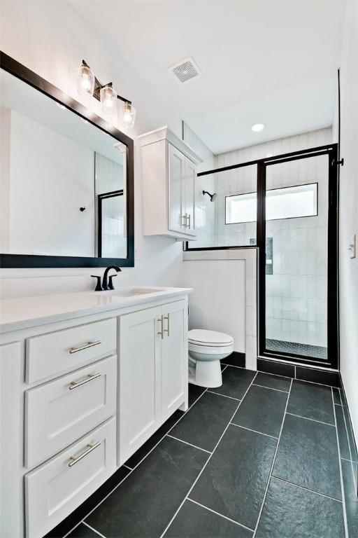 full bathroom with visible vents, a shower stall, toilet, tile patterned floors, and vanity