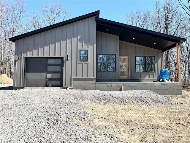 view of front facade with board and batten siding, driveway, and a garage