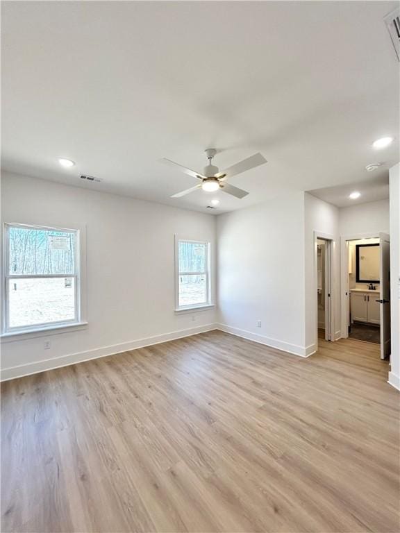 spare room with light wood-style floors, visible vents, and baseboards