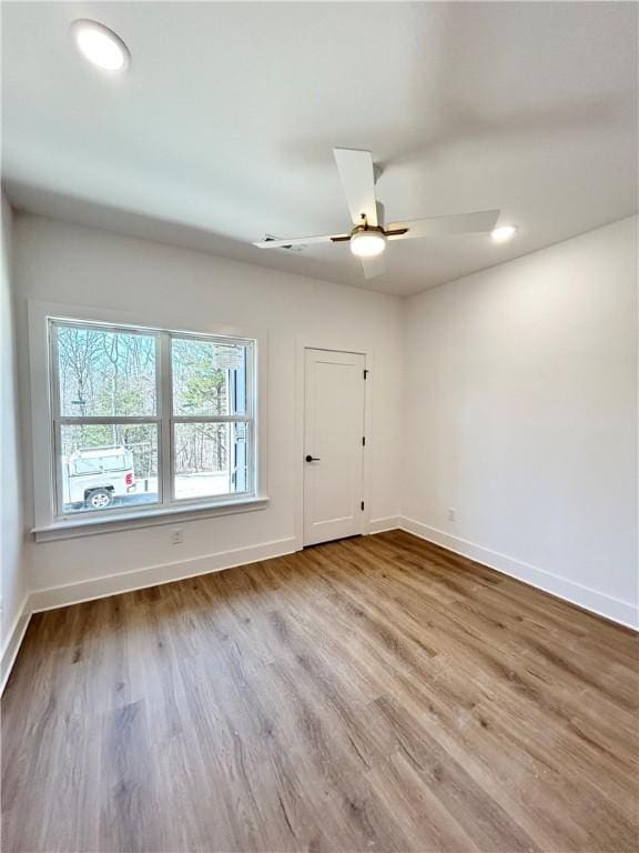 empty room with baseboards, a ceiling fan, and wood finished floors