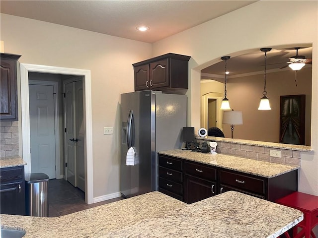 kitchen featuring ceiling fan, dark tile patterned floors, dark brown cabinetry, arched walkways, and stainless steel fridge