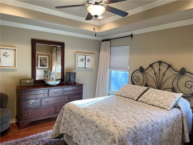 bedroom featuring a ceiling fan, a raised ceiling, crown molding, and dark wood-style floors