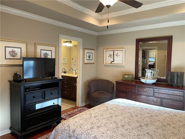 bedroom with wood finished floors, baseboards, ensuite bath, and crown molding