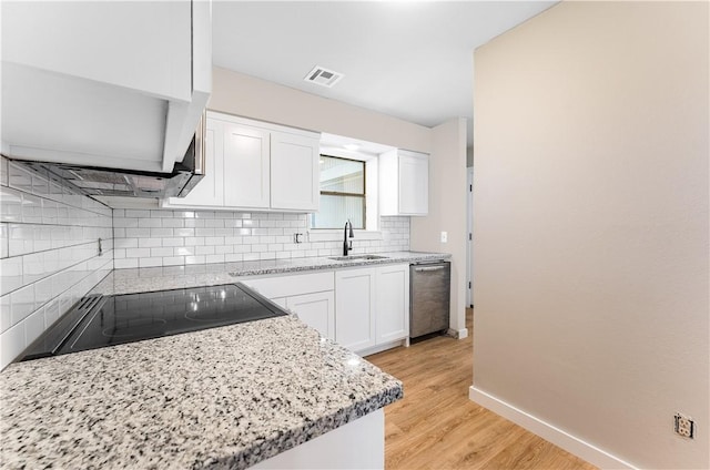 kitchen with visible vents, backsplash, black electric stovetop, white cabinetry, and a sink