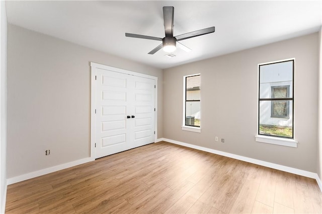 unfurnished bedroom with multiple windows, baseboards, and light wood-type flooring