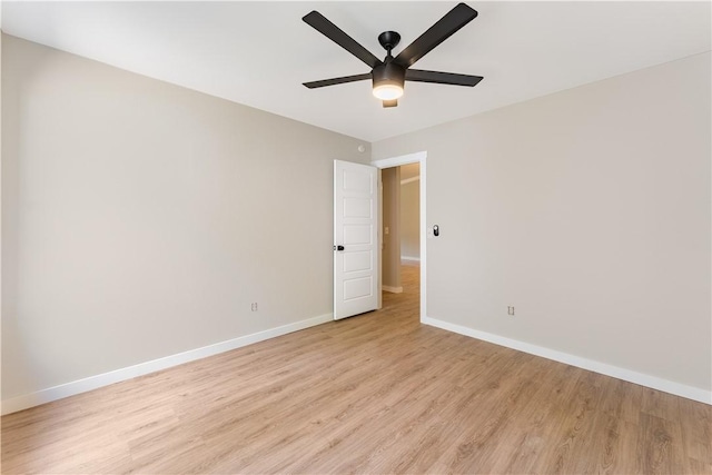 spare room featuring light wood-style flooring, a ceiling fan, and baseboards