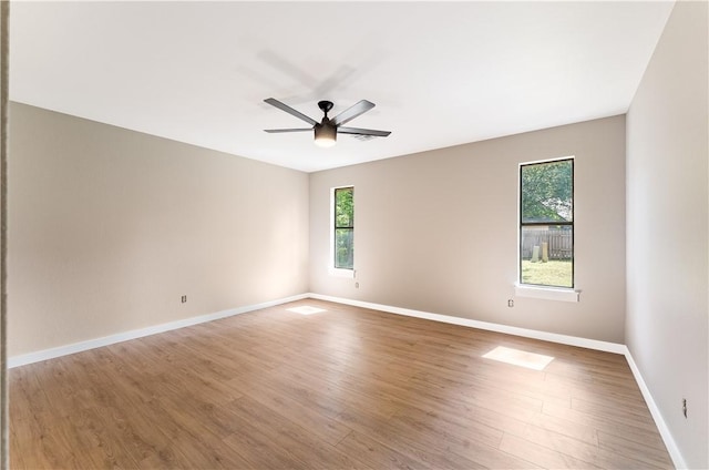 empty room featuring a wealth of natural light, a ceiling fan, and wood finished floors