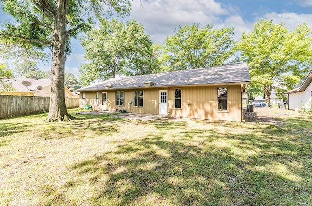 rear view of property featuring a lawn and fence