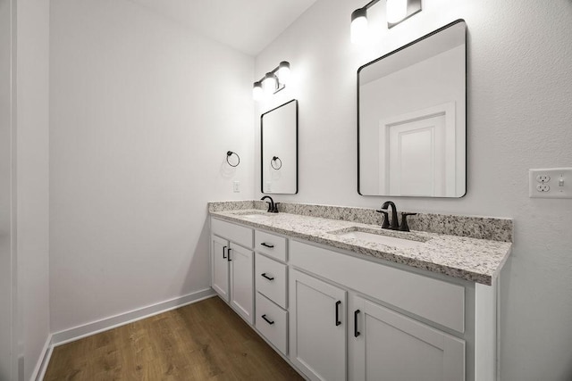 full bathroom with double vanity, wood finished floors, baseboards, and a sink