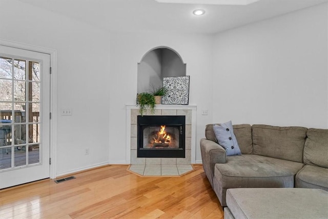 living area with recessed lighting, visible vents, light wood-style flooring, and a tile fireplace