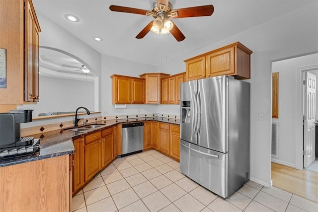 kitchen featuring dark stone countertops, a ceiling fan, light tile patterned flooring, a sink, and stainless steel appliances