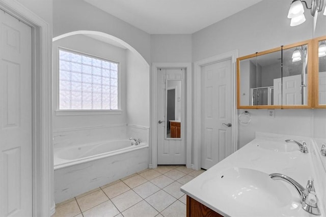 full bathroom with tile patterned flooring, double vanity, a bath, and a sink