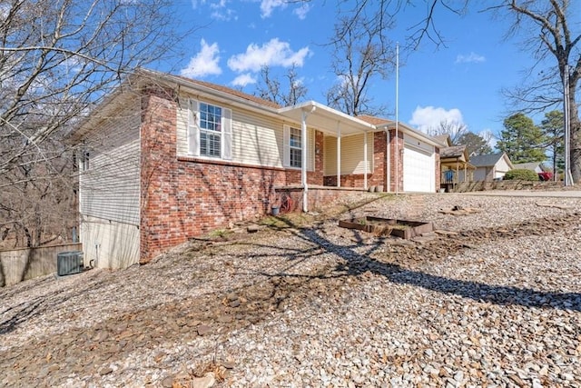 ranch-style home featuring cooling unit, driveway, a porch, a garage, and brick siding