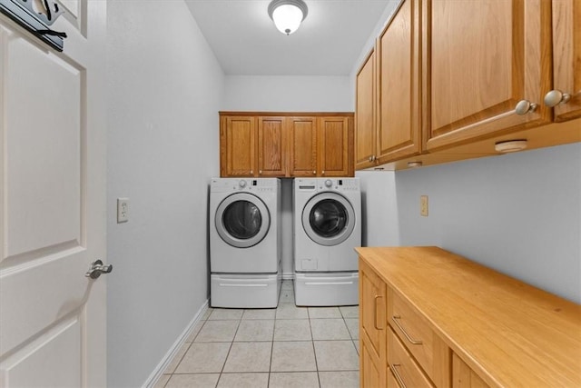 clothes washing area featuring baseboards, cabinet space, light tile patterned flooring, and washing machine and clothes dryer