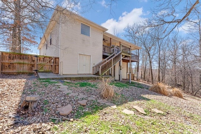 back of property with a ceiling fan, a patio, fence, a wooden deck, and stairs