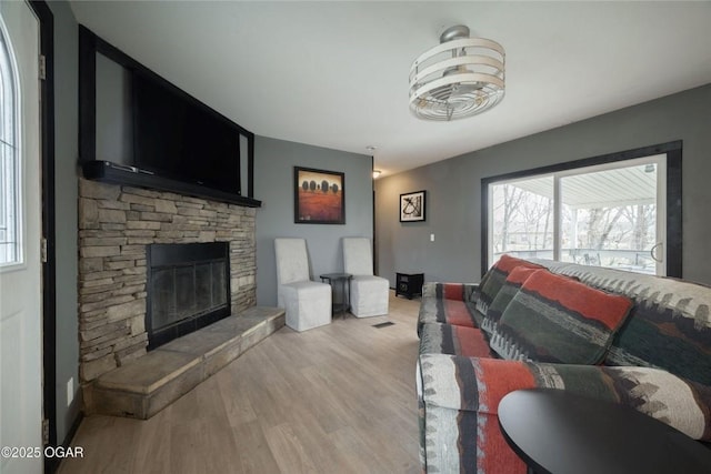 living room with a stone fireplace and wood finished floors