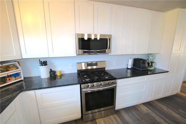 kitchen with white cabinets, appliances with stainless steel finishes, dark stone counters, and dark wood-style flooring