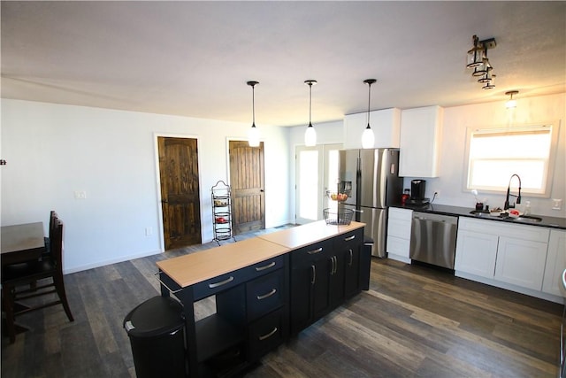 kitchen with a sink, a center island, white cabinetry, stainless steel appliances, and dark wood-style flooring