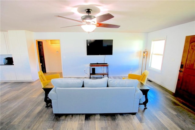 living area featuring wood finished floors, baseboards, and ceiling fan