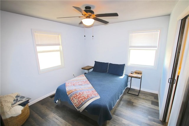 bedroom with baseboards, multiple windows, and wood finished floors