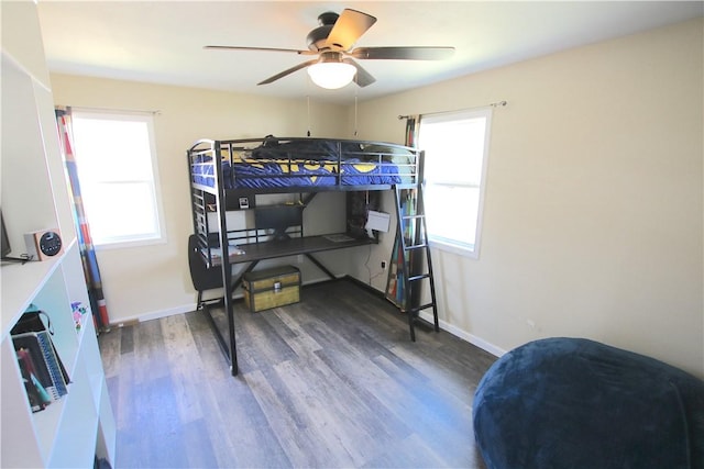 bedroom featuring baseboards, wood finished floors, and a ceiling fan