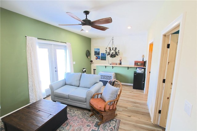 living room featuring baseboards, light wood-style floors, and a ceiling fan