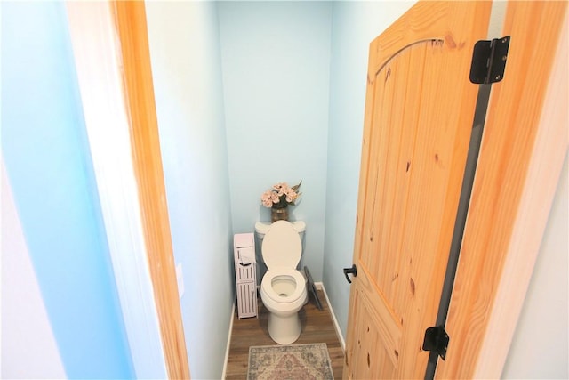 bathroom with toilet, baseboards, and wood finished floors