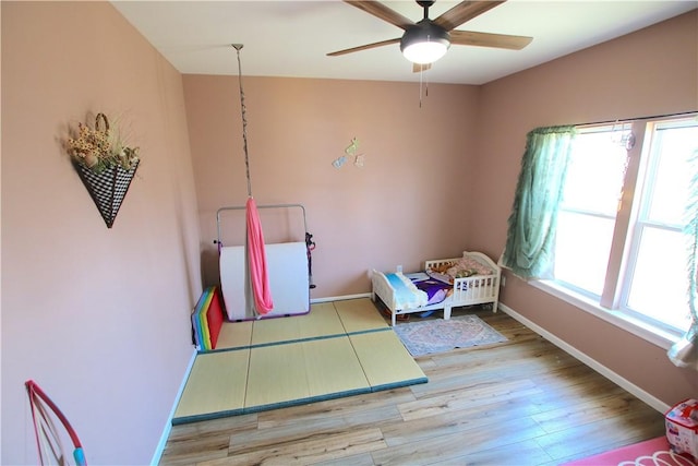 bedroom with ceiling fan, baseboards, and wood finished floors